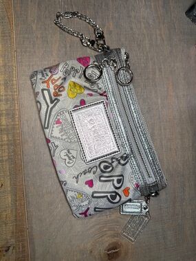 Coach Poppy graffiti print wristlet clutch with silver metallic accents.